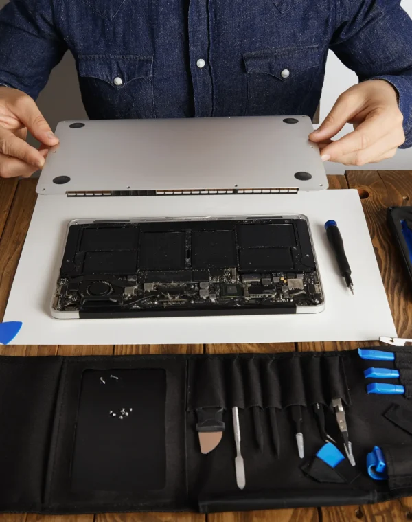 service-man-opens-backside-topcase-cover-computer-laptop-before-repairing-cleaning-fixing-it-with-his-professional-tools-from-toolkit-box-near-wooden-table-front-view